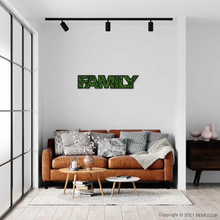 ein Wohnzimmer mit einer Couch und einem Tisch, darüber an der Wand ein Familienschild, moosbild, mooswand, moos pflanzen, moos, moos deko, moos art