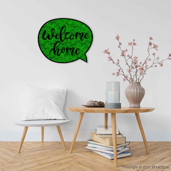 ein Zimmer mit einem Tisch und einer Vase mit Blumen darauf und einem Schild mit der Aufschrift „Willkommen zu Hause“., moosbild, mooswand, moos pflanzen, moos, moos deko, moos art